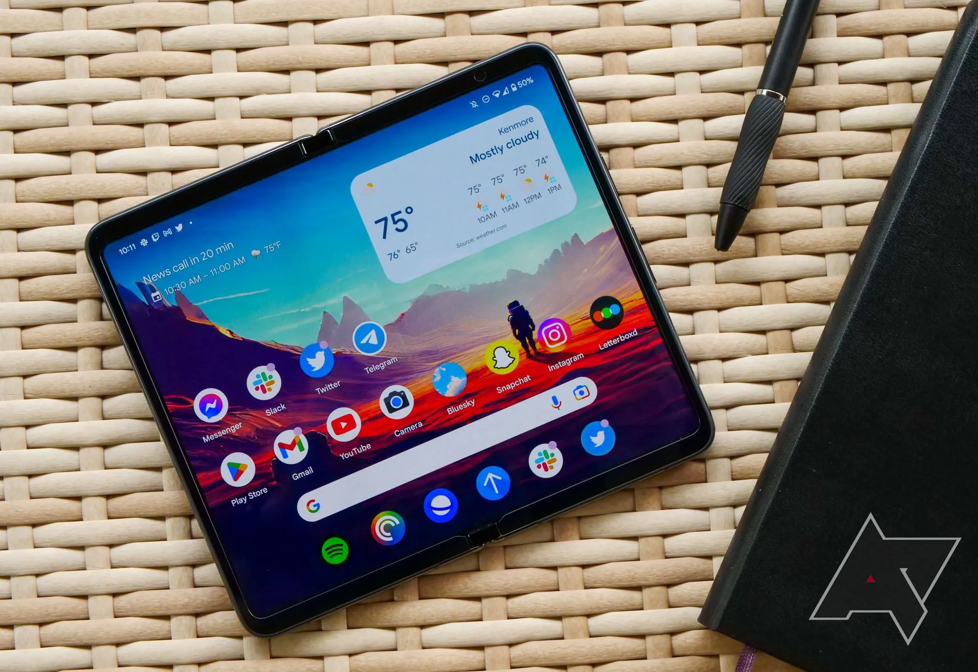 Google Pixel Fold trên bàn cạnh sổ tay, thể hiện tính năng làm việc.