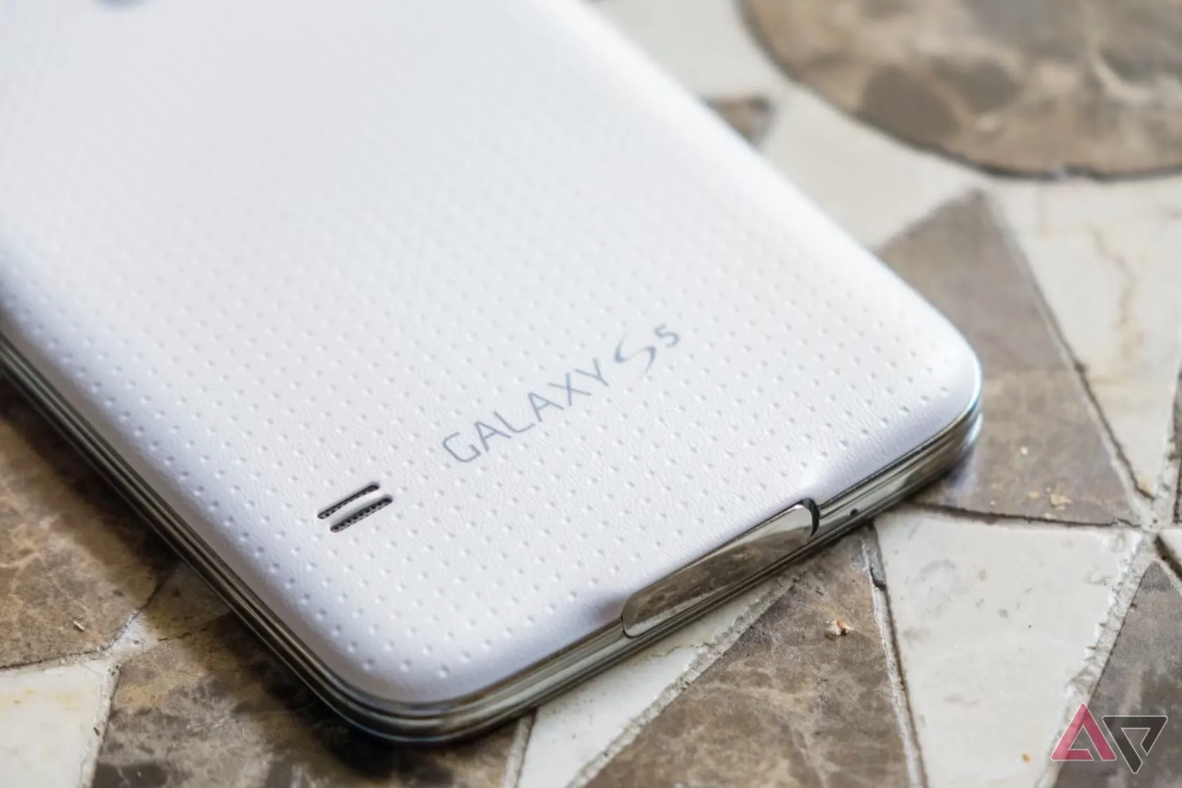 Mặt lưng của điện thoại Samsung Galaxy S5 màu trắng, cho thấy chất liệu nhựa sần đặc trưng, cảm biến nhịp tim và cụm camera, minh họa thiết kế bị chê bai nặng nề.