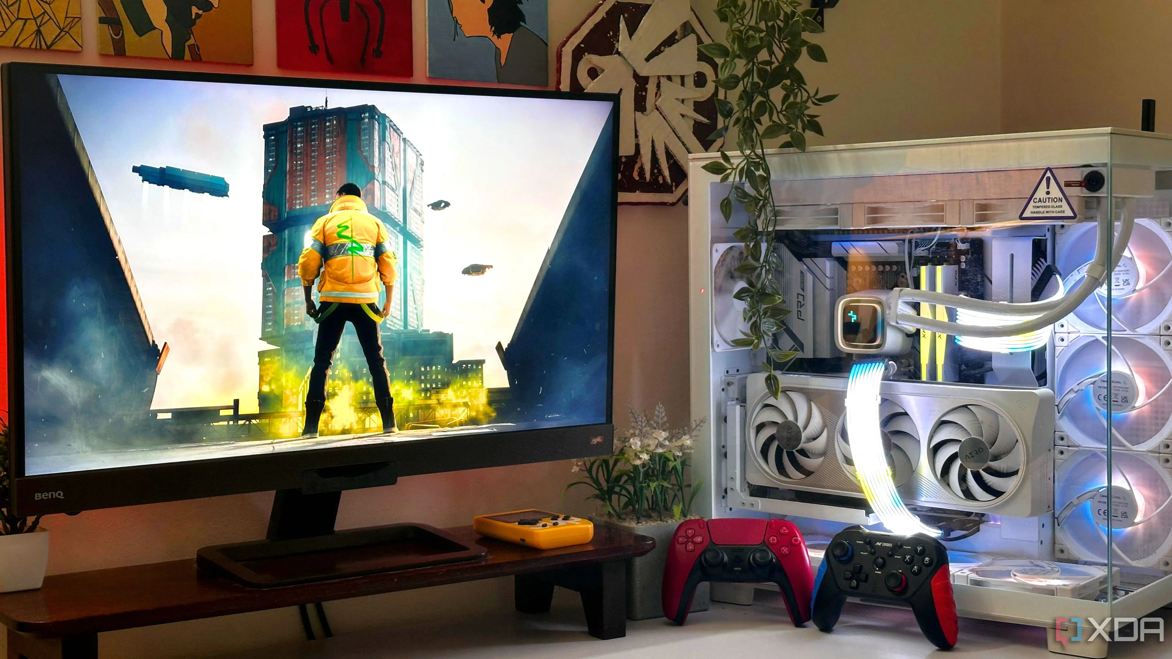 Một bộ PC chơi game với tựa game Cyberpunk 2077 hiển thị trên màn hình và hai tay cầm game, biểu thị trải nghiệm chơi game có thể bị ảnh hưởng bởi hiệu suất hệ thống.