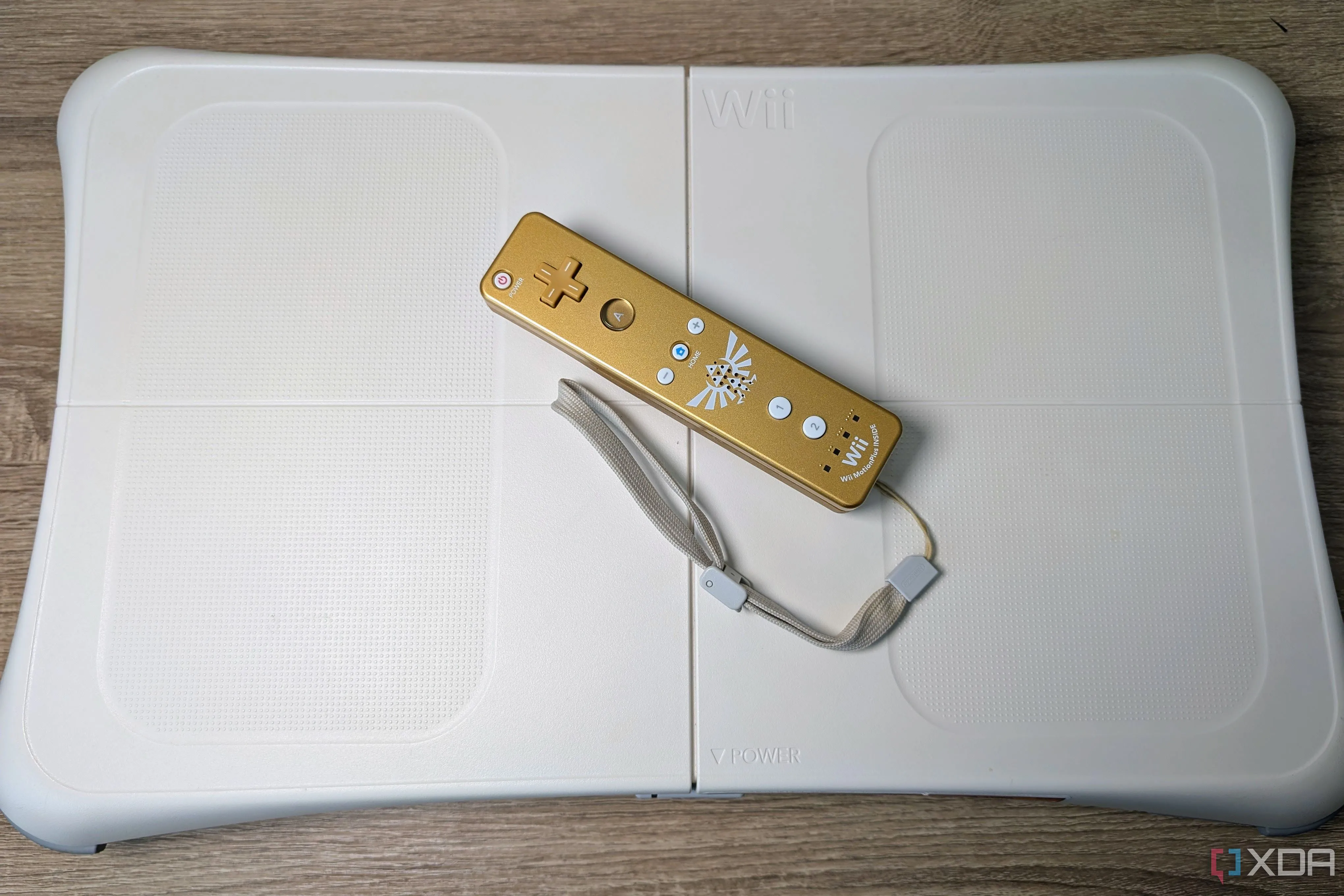 Wii Balance Board màu trắng đi kèm tay cầm Wii-mote vàng, biểu tượng của kỷ nguyên game thể dục.