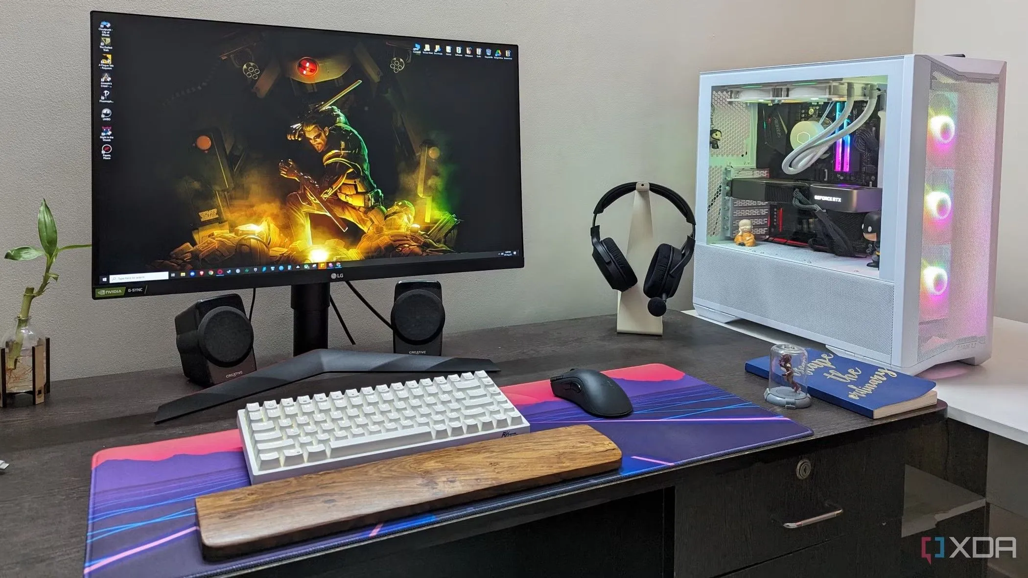 Bàn máy tính với bàn di chuột lớn, bàn phím, chuột và tai nghe, thể hiện một setup gaming được chăm chút