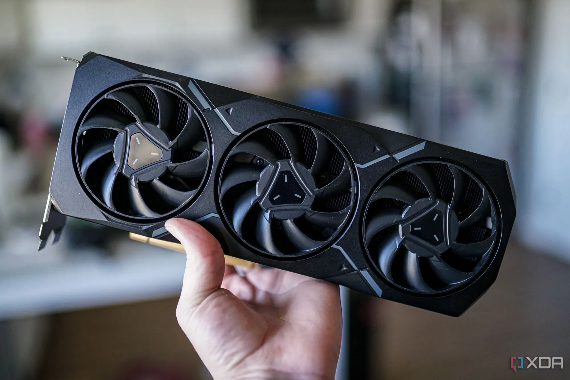 Bàn tay cầm card đồ họa AMD Radeon RX 7900 XT, biểu tượng của hiệu năng cao nhưng cũng nhắc nhở về những lựa chọn thay thế trên thị trường cũ.