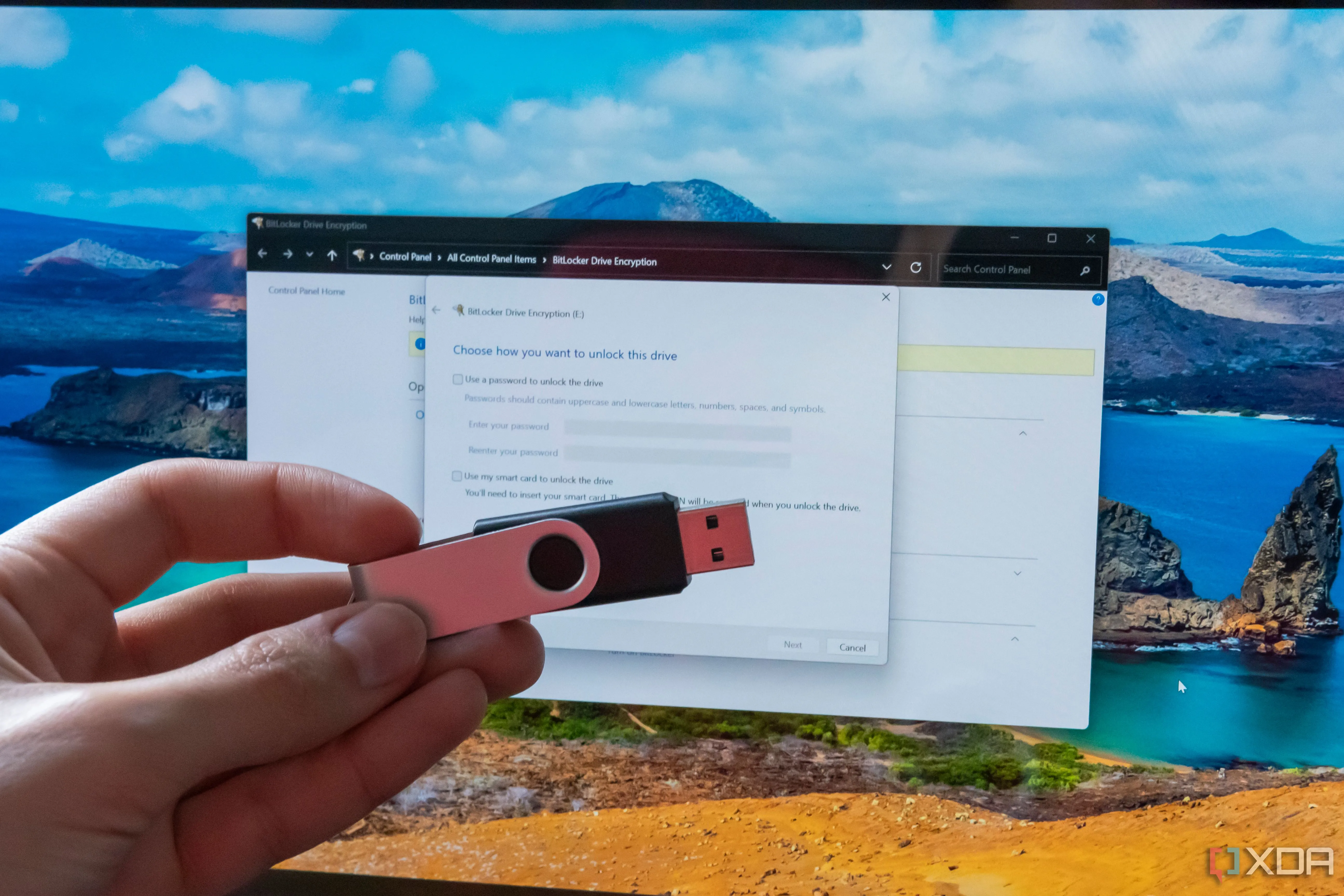 Bàn tay cầm USB flash drive trước màn hình máy tính hiển thị cài đặt BitLocker