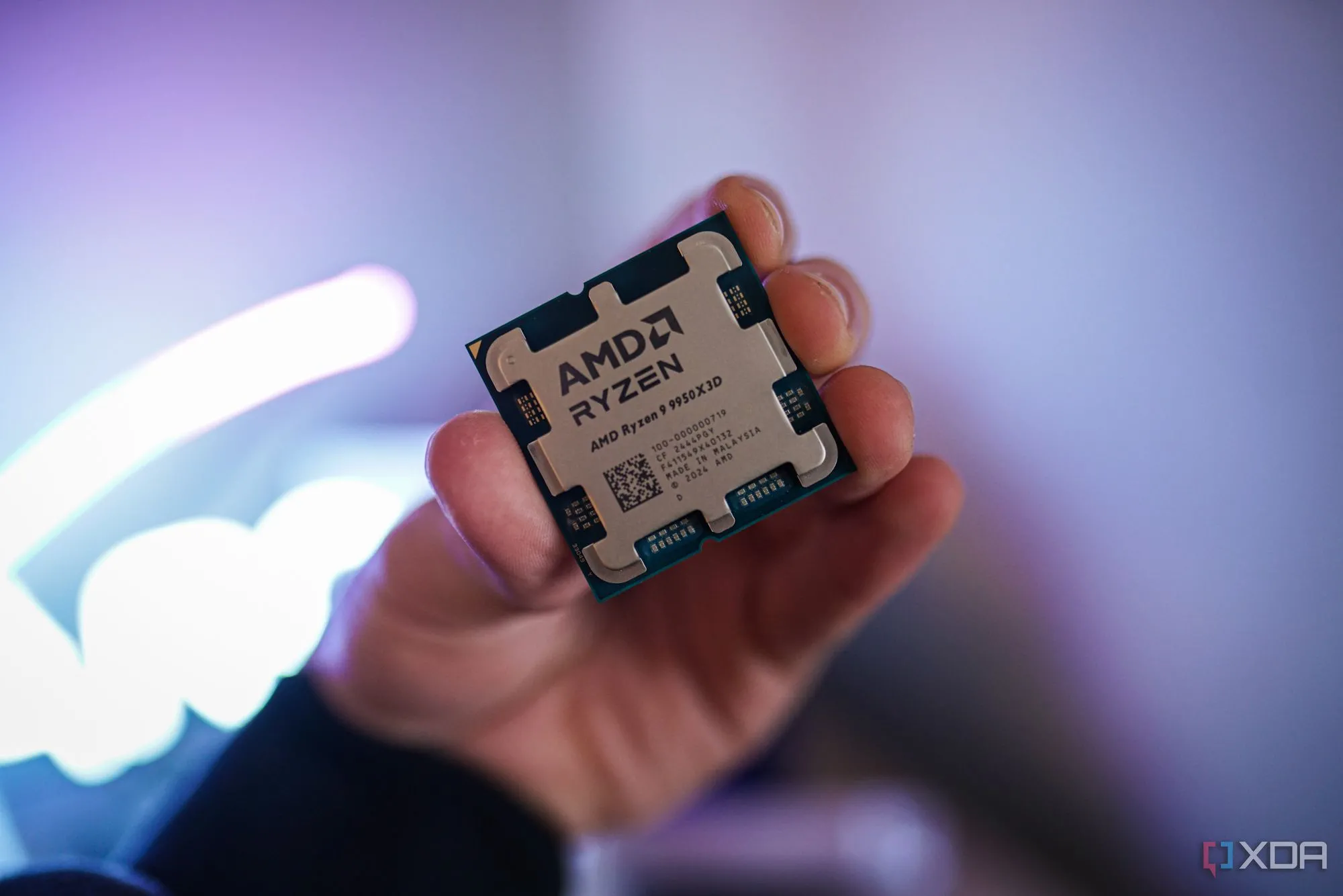 Bàn tay đang cầm CPU AMD Ryzen 9 9950X3D, cho thấy kích thước nhỏ gọn của chip xử lý