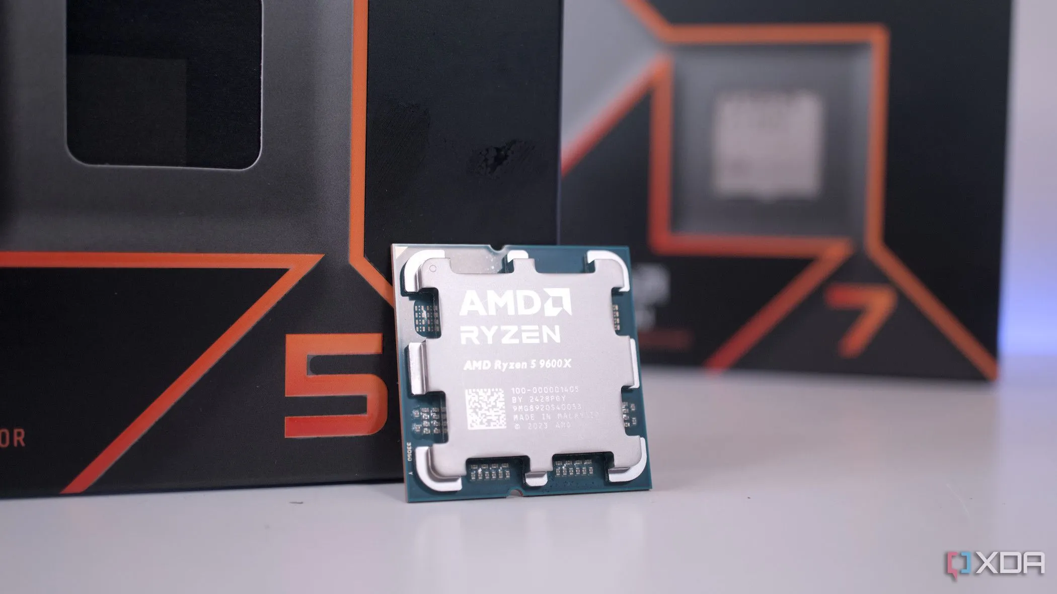 Bộ vi xử lý AMD Ryzen 5 9600X nổi bật trước hộp của Ryzen 7, tượng trưng cho sự so sánh giữa các dòng CPU và lựa chọn tối ưu về hiệu năng