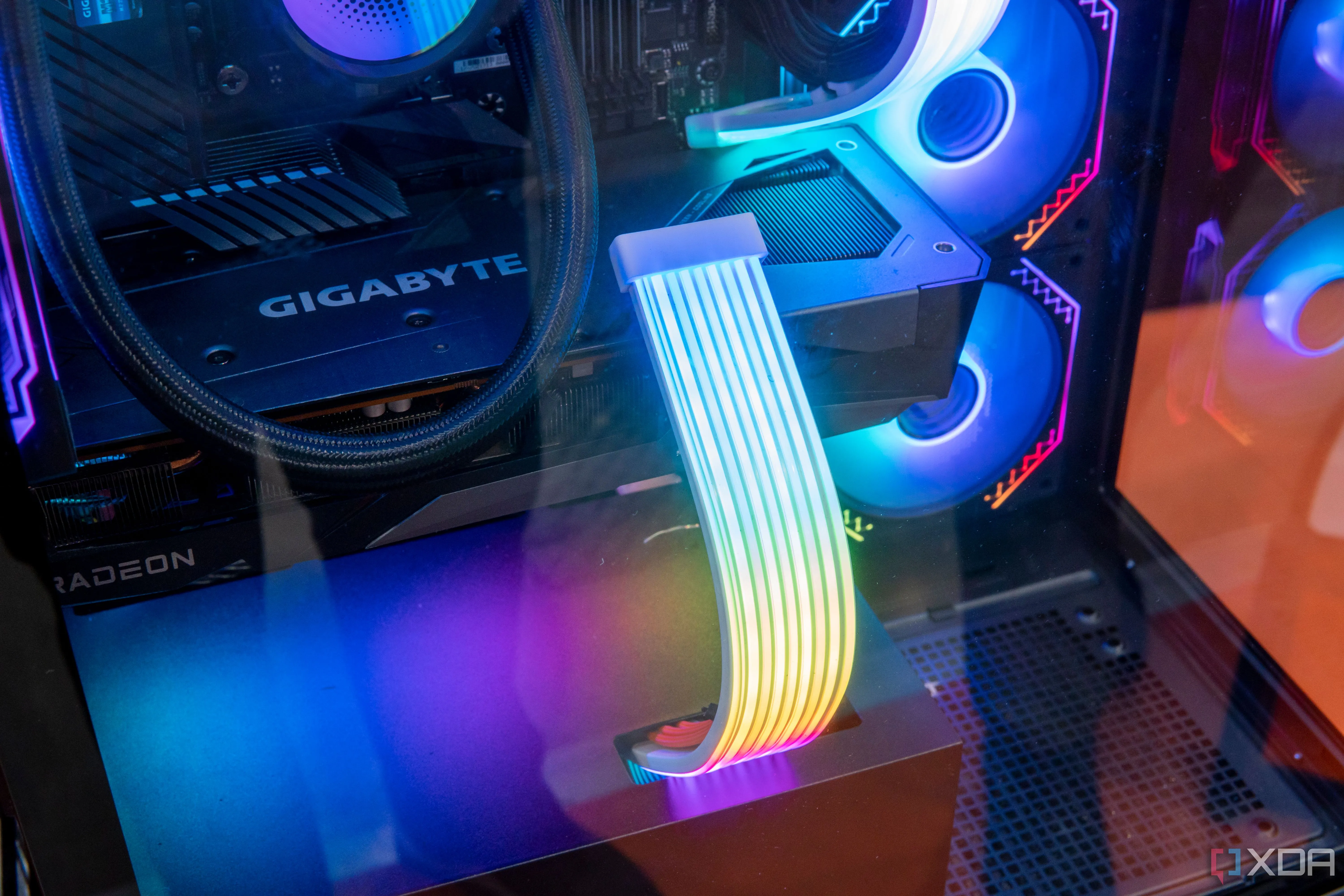Cận cảnh các dây cáp nguồn RGB được bọc lưới màu đen bên trong một chiếc PC, tạo điểm nhấn ánh sáng độc đáo