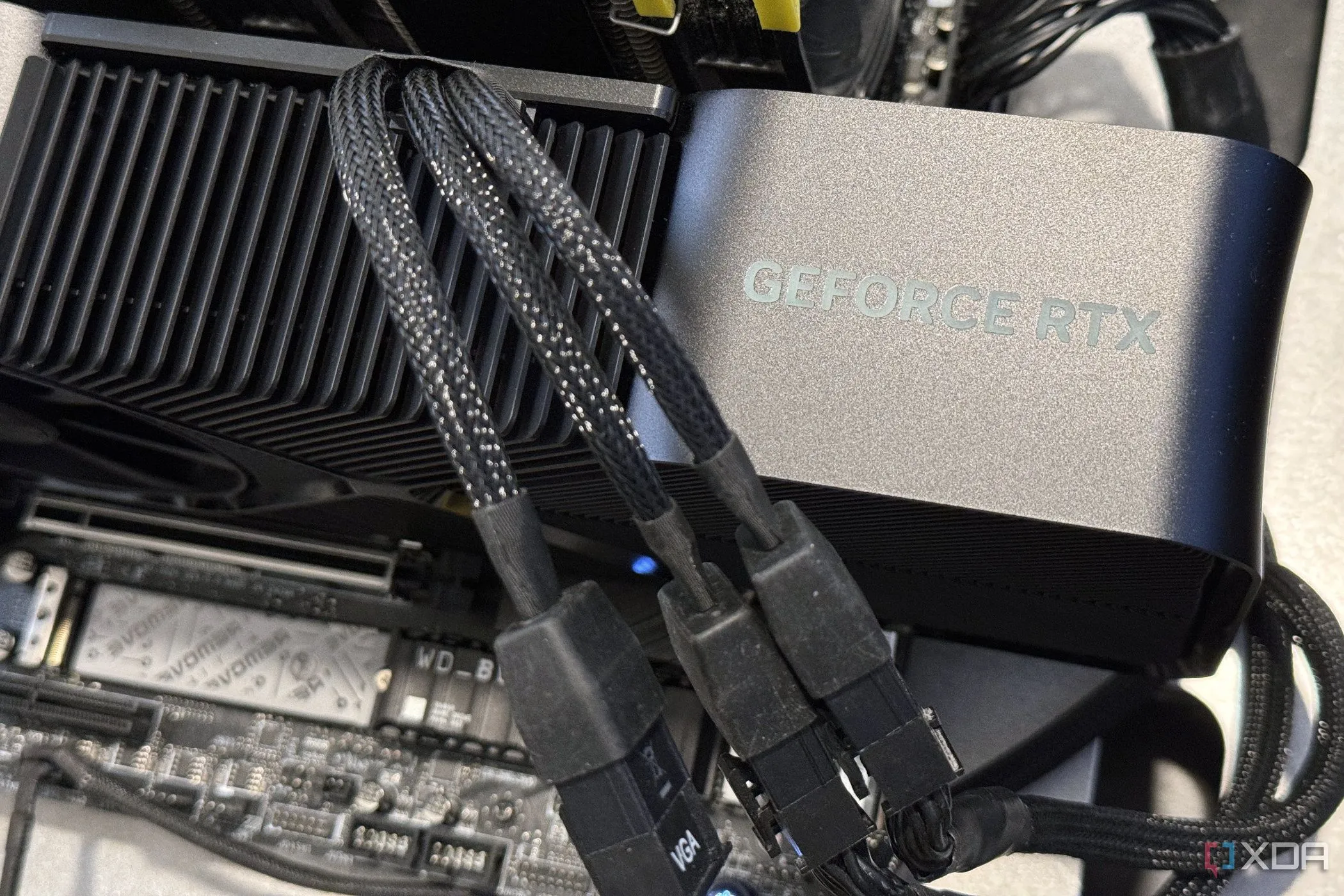 Card đồ họa NVIDIA GeForce RTX 4080 Super FE gắn trên bo mạch chủ với ba dây nguồn, thể hiện khả năng ép xung