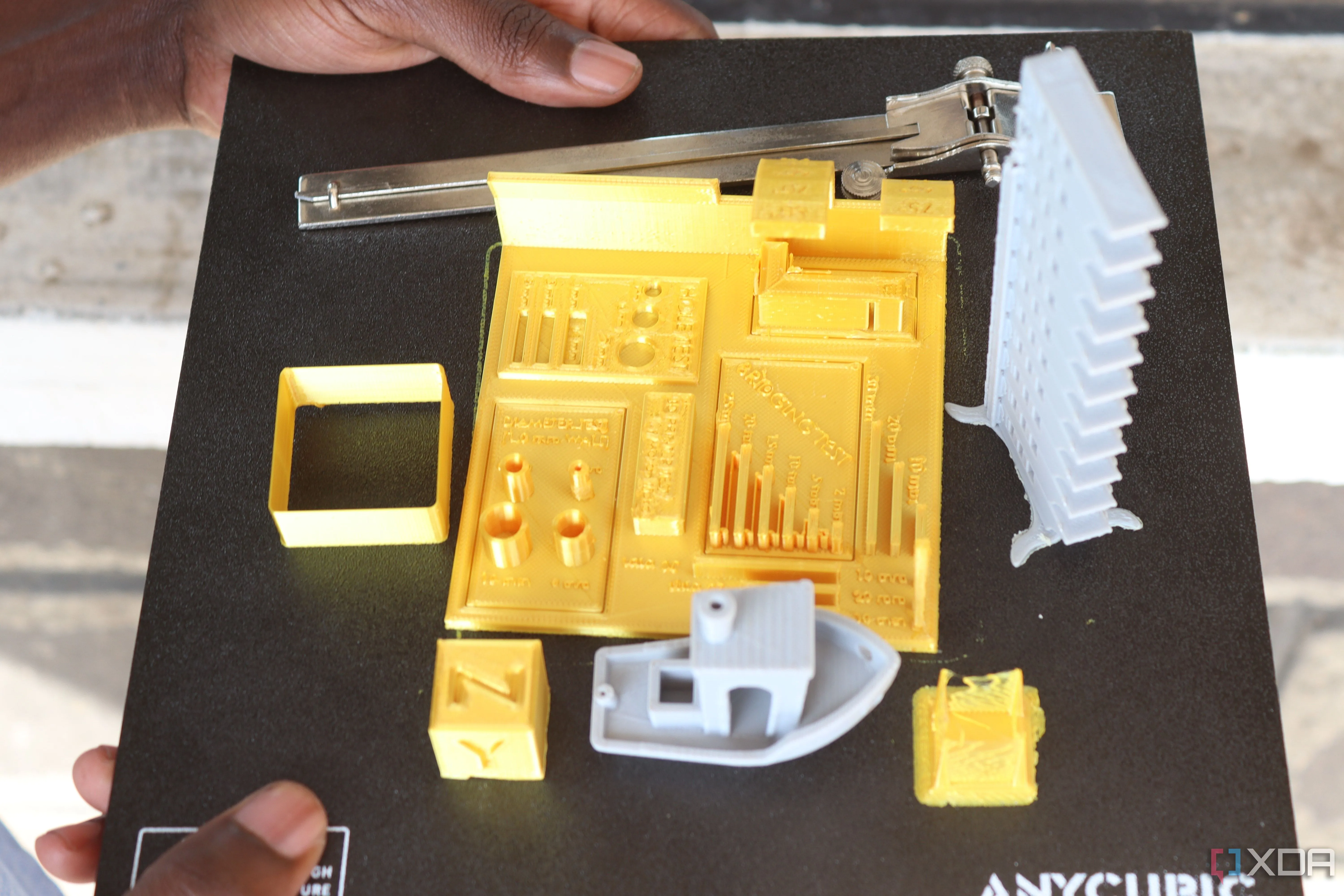 Hình ảnh các mô hình 3D đã in xong được đặt trên bề mặt bàn in của máy in 3D, minh họa kích thước vùng in