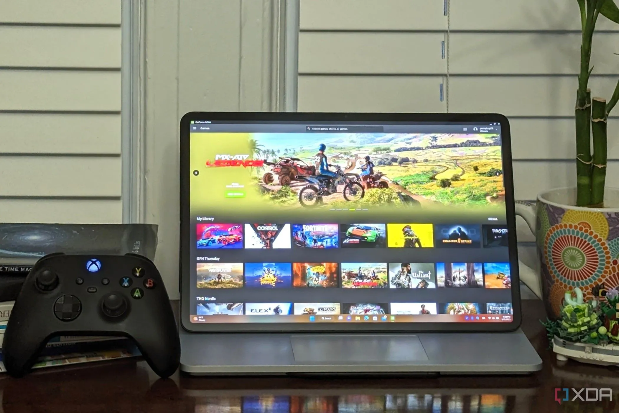Laptop hiển thị giao diện GeForce Now Ultimate cùng tay cầm Xbox, minh họa khả năng chơi game tiện lợi trên nền tảng đám mây