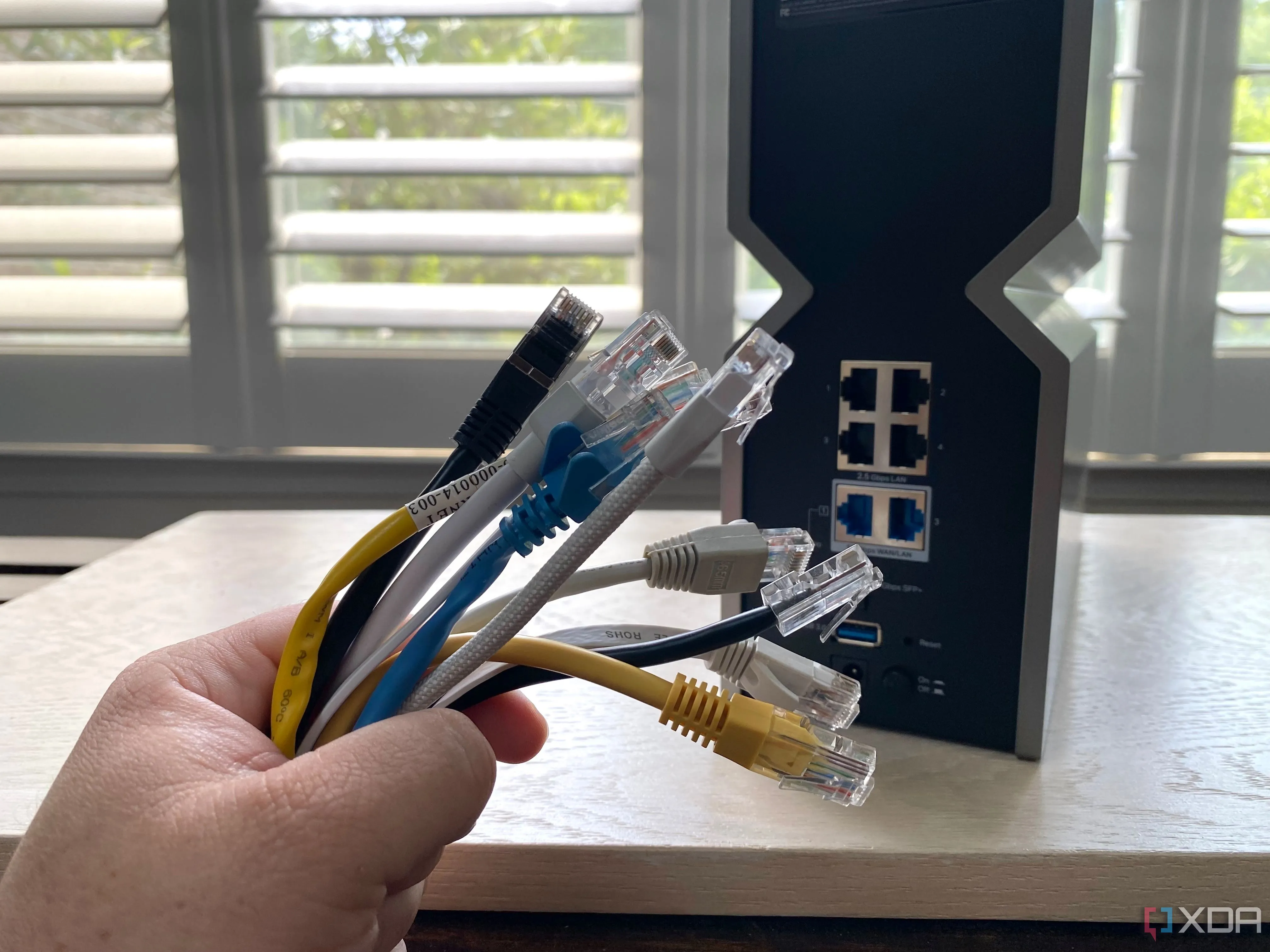 Loạt cáp Ethernet nhiều màu sắc đặt trước một router Wi-Fi, nhấn mạnh tầm quan trọng của kết nối mạng có dây.