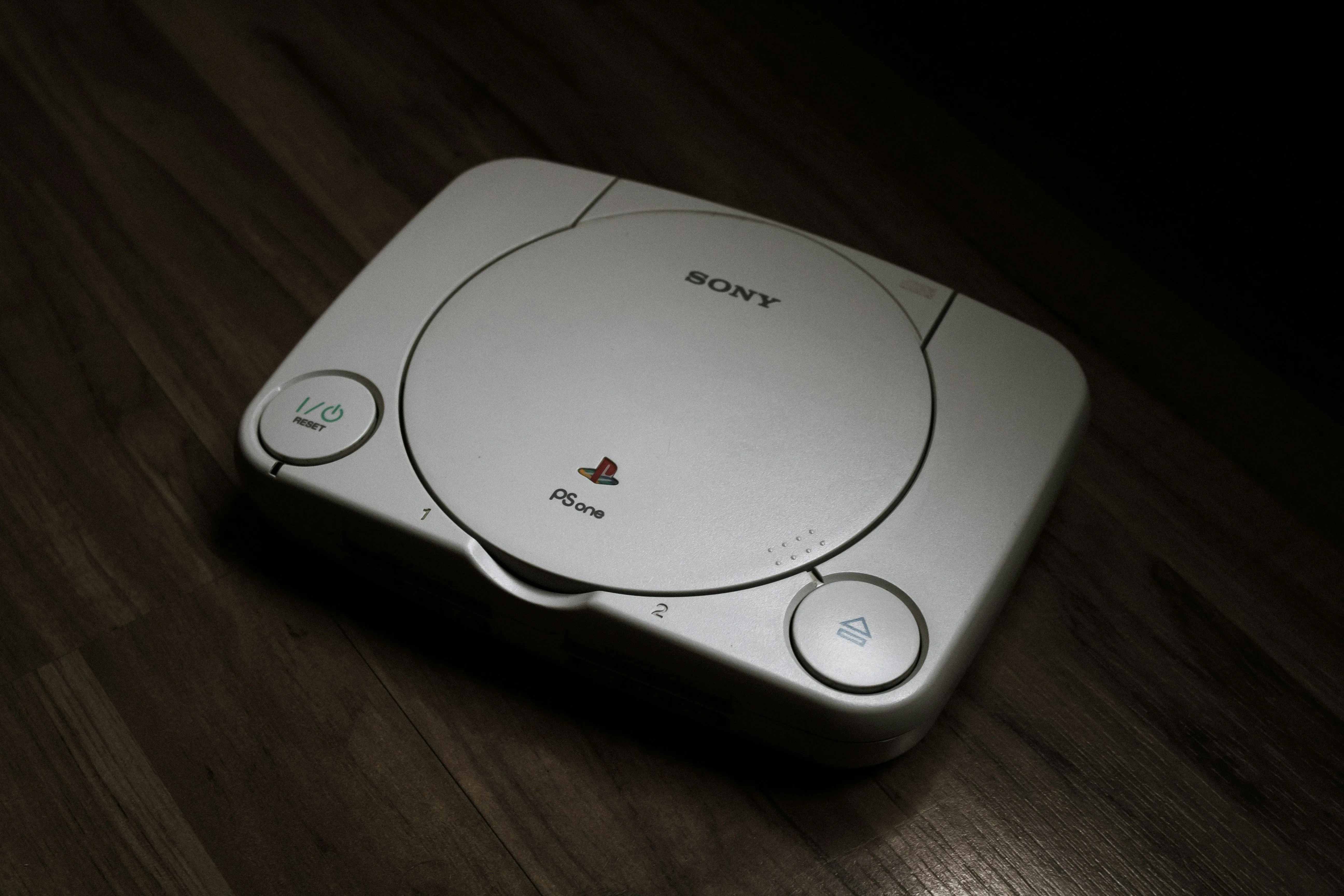 Máy chơi game PlayStation 1 đặt trên sàn gỗ, đánh dấu sự chuyển mình của console
