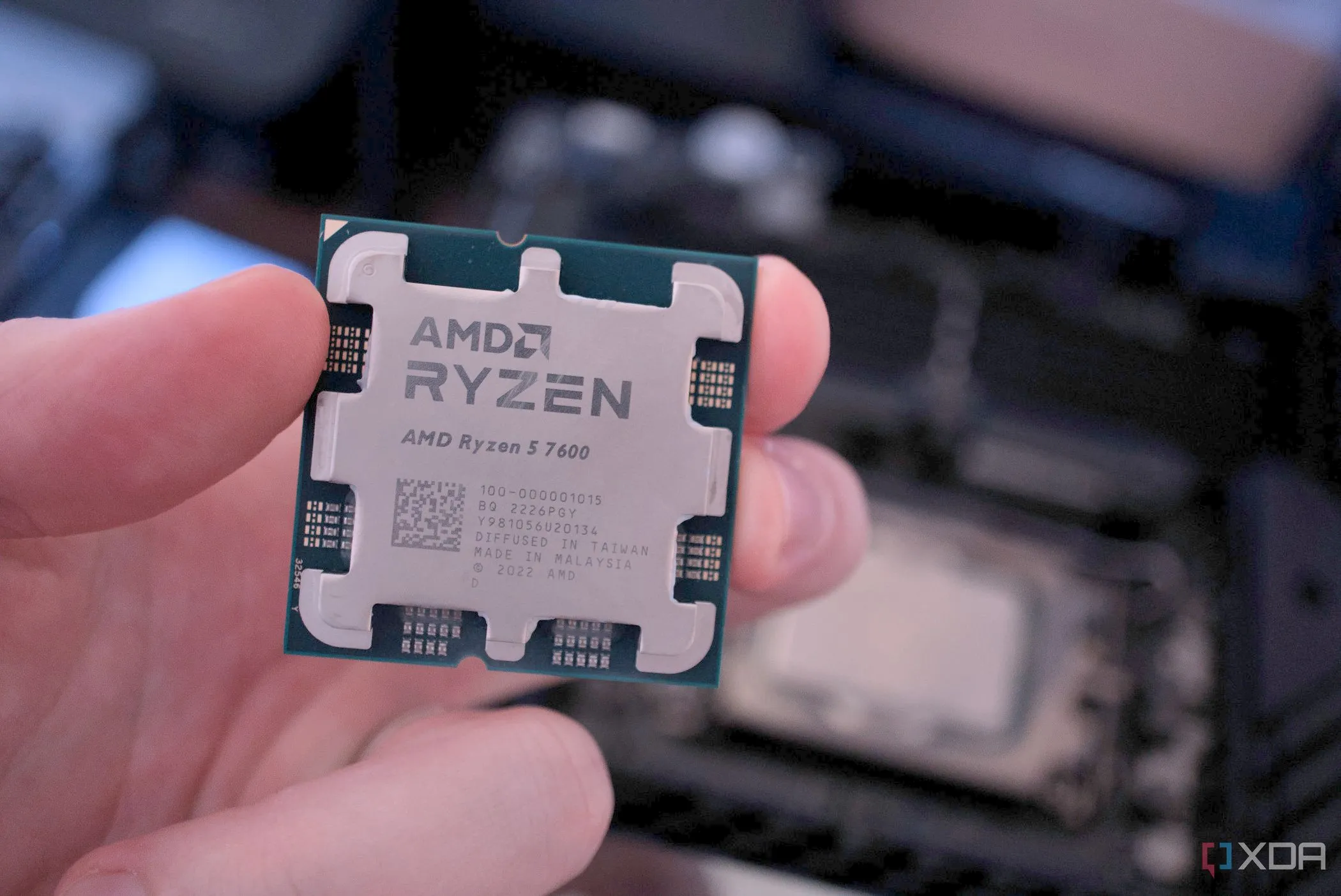 Một người đang cầm CPU AMD Ryzen 7 7700 và một CPU Intel, so sánh các vi xử lý hiện đại
