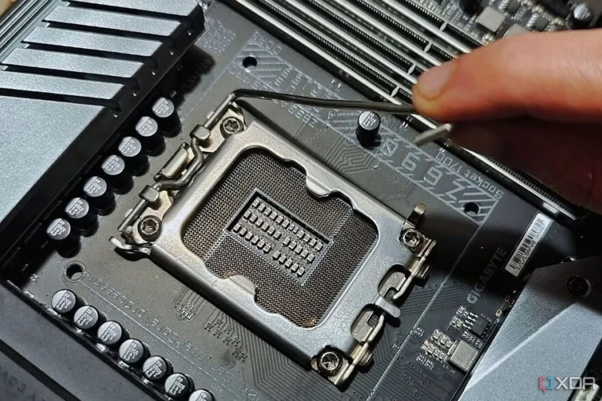 Một người đang giữ cần gạt kim loại cạnh socket CPU trên bo mạch chủ, minh họa vị trí lắp đặt CPU