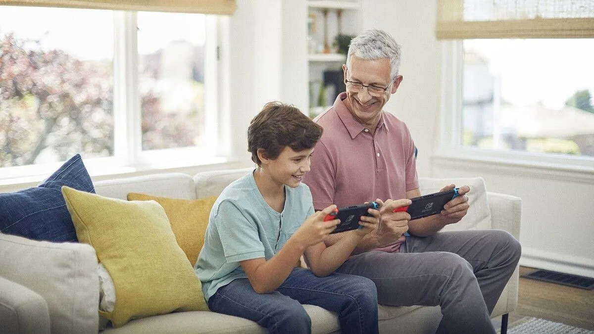 Người cha và con trai đang cùng chơi Nintendo Switch, minh họa khả năng chơi game gia đình của console này