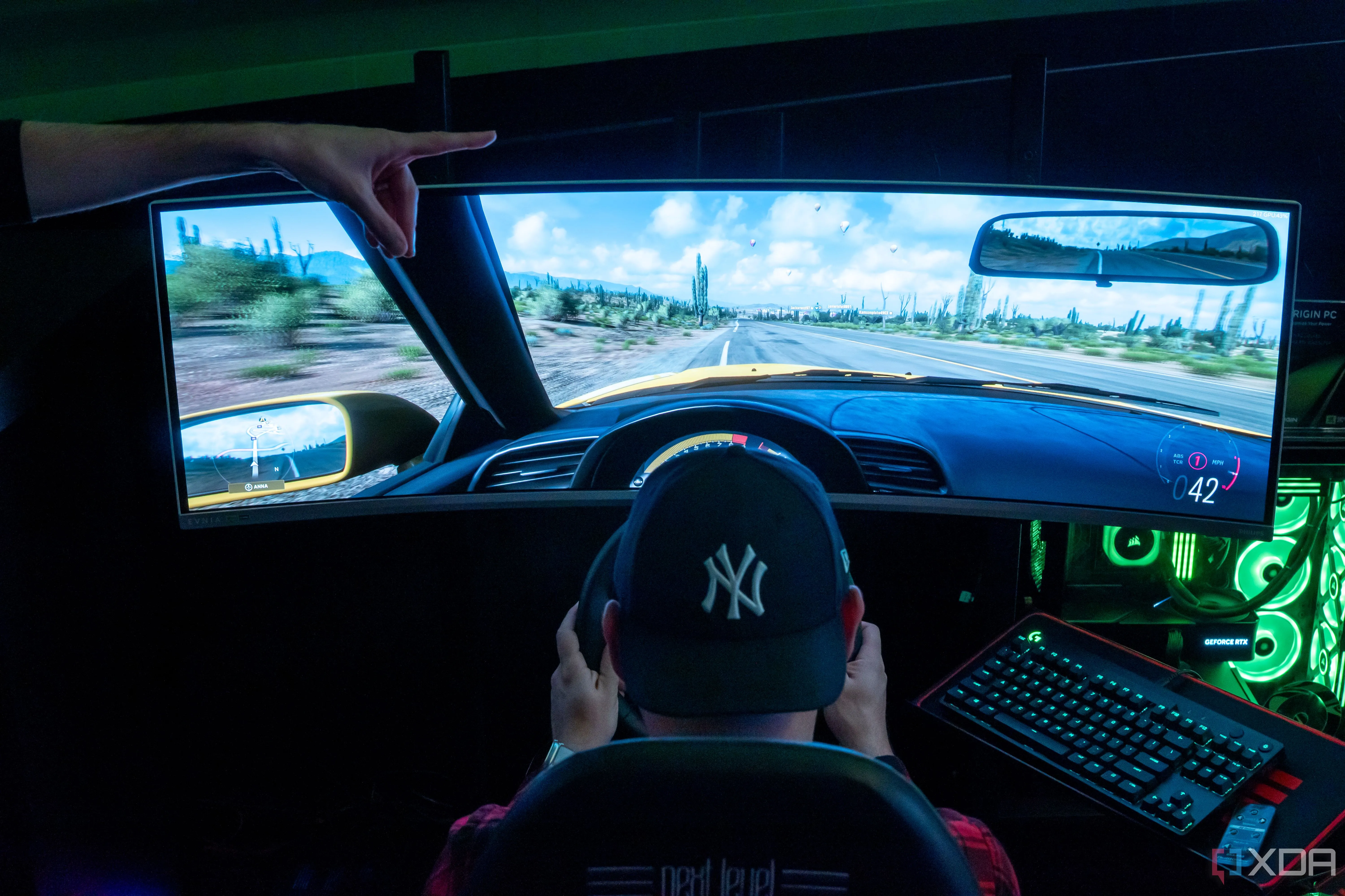 Người đàn ông ngồi trên ghế gaming và sử dụng vô lăng để chơi trò chơi điện tử trên màn hình lớn