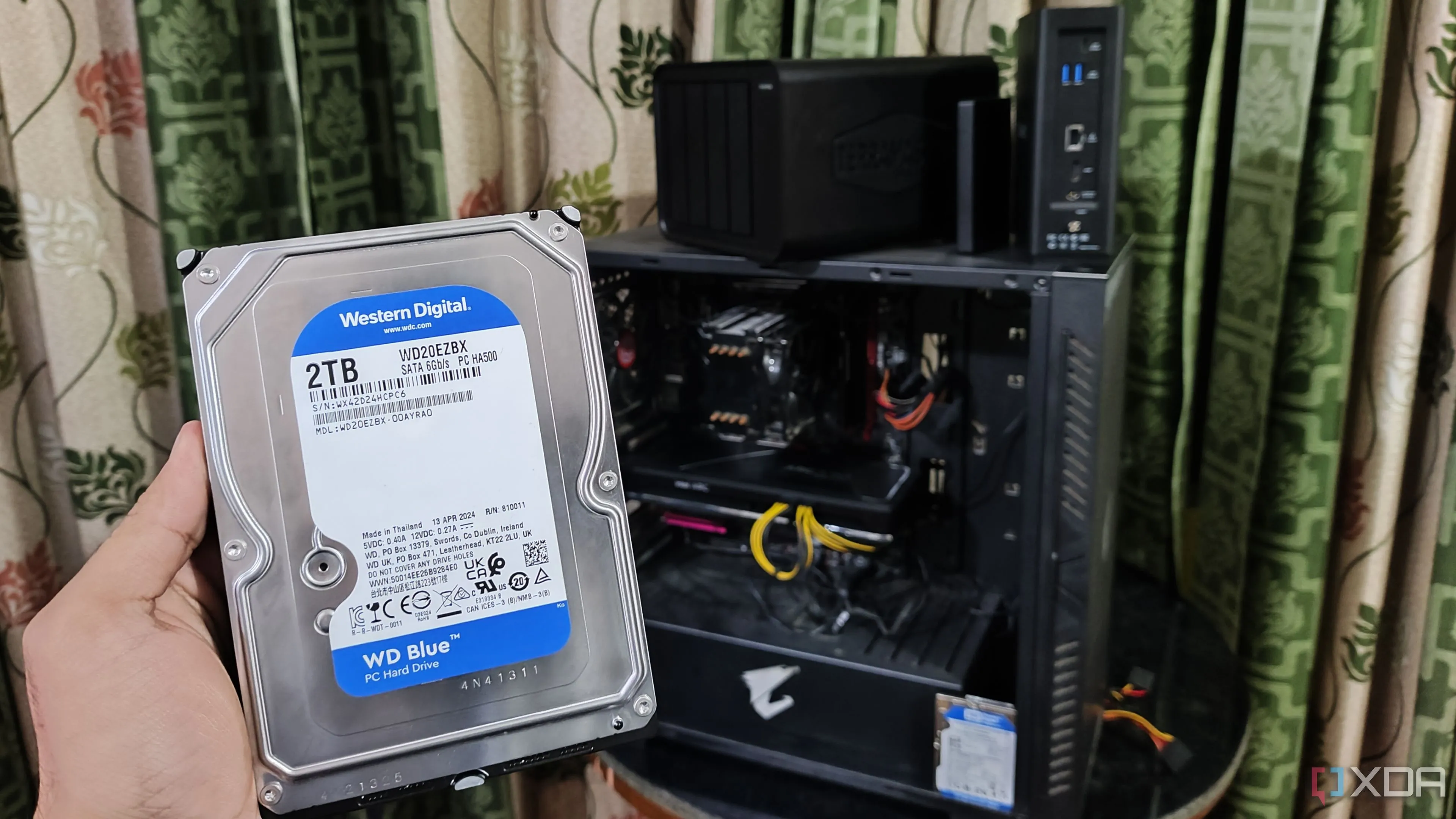 Người dùng cầm ổ cứng trước các thiết bị NAS TerraMaster và PC, minh họa quá trình thiết lập sao lưu dữ liệu.