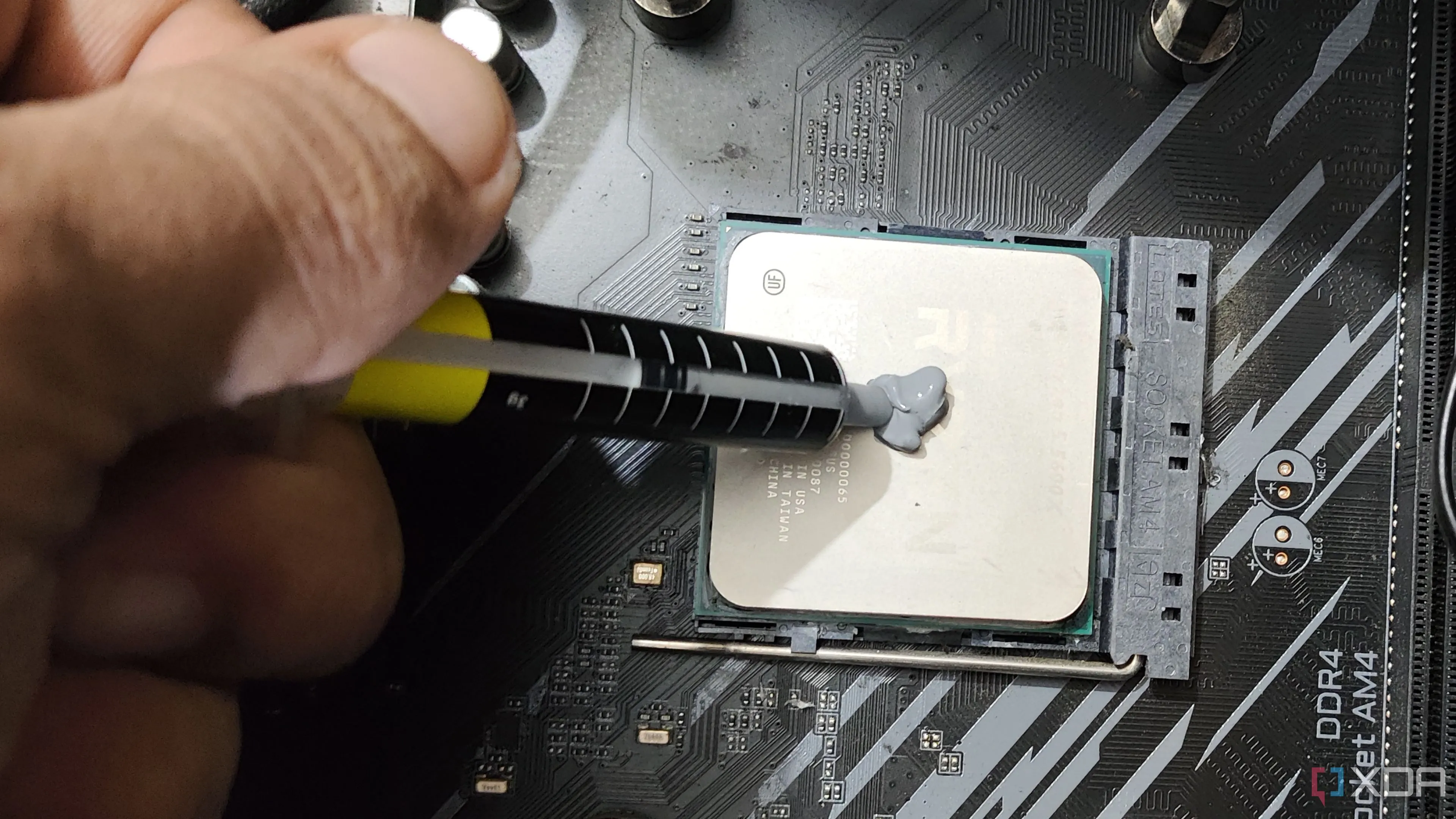 Người dùng đang bôi keo tản nhiệt lên bộ vi xử lý AMD Ryzen 5 5600X, minh họa quy trình thay keo tản nhiệt cho CPU.