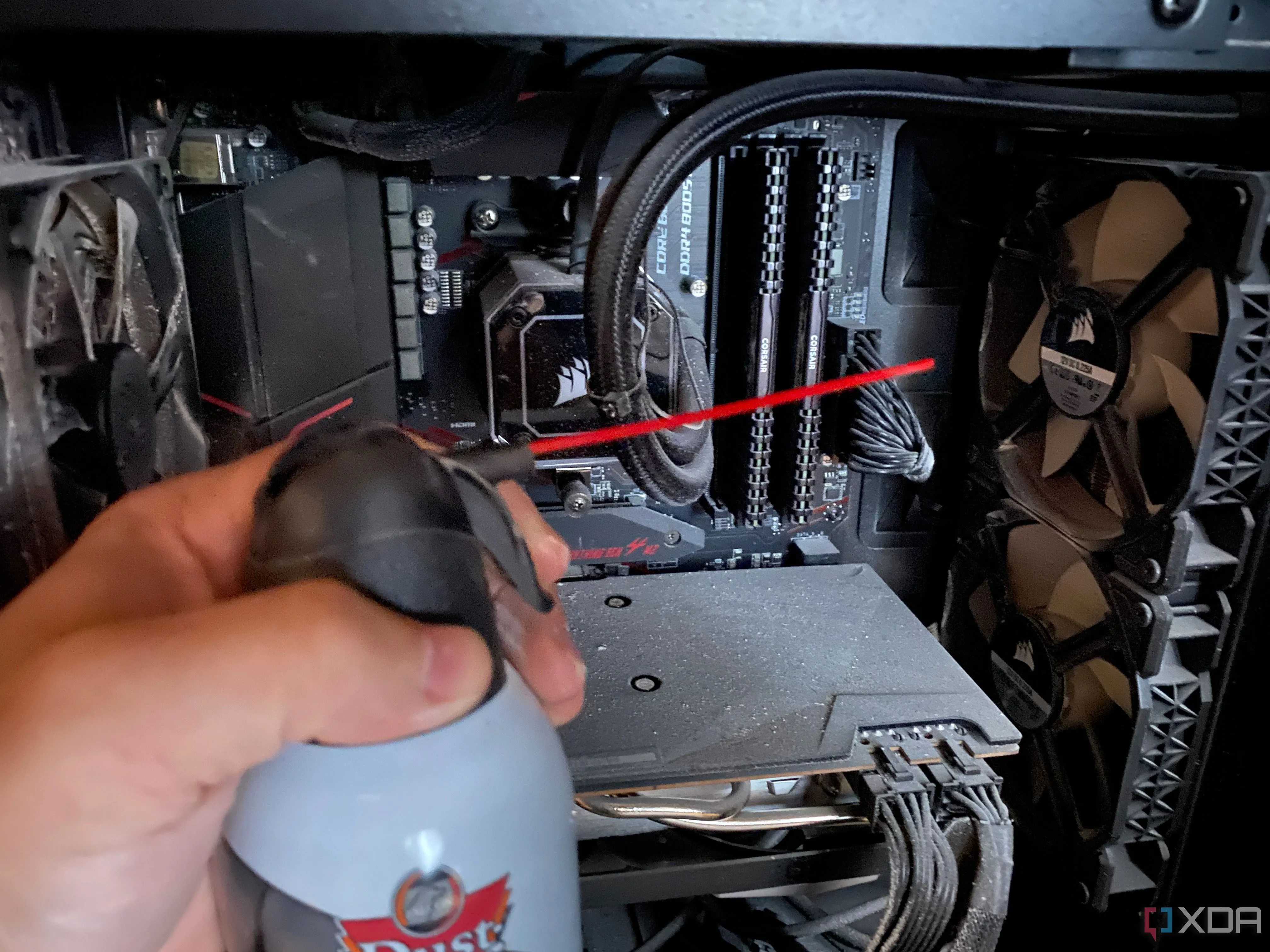 Người dùng đang thổi bụi ra khỏi vỏ case PC bằng bình khí nén, minh họa việc vệ sinh máy tính để cải thiện tản nhiệt.