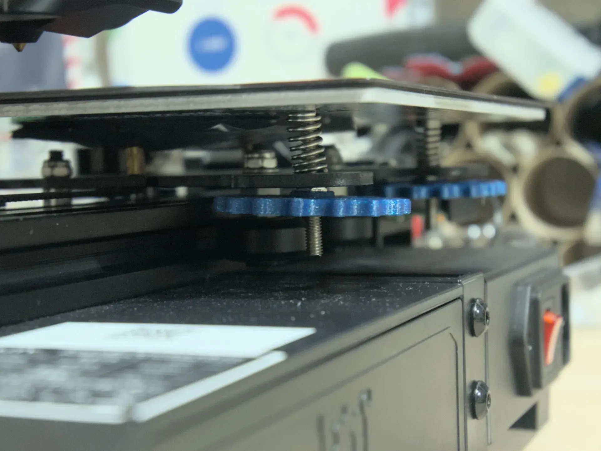 Nút vặn cân bàn của máy in 3D Ender 2 Pro, đại diện cho phương pháp cân bàn truyền thống cần thay thế bằng đệm silicone.