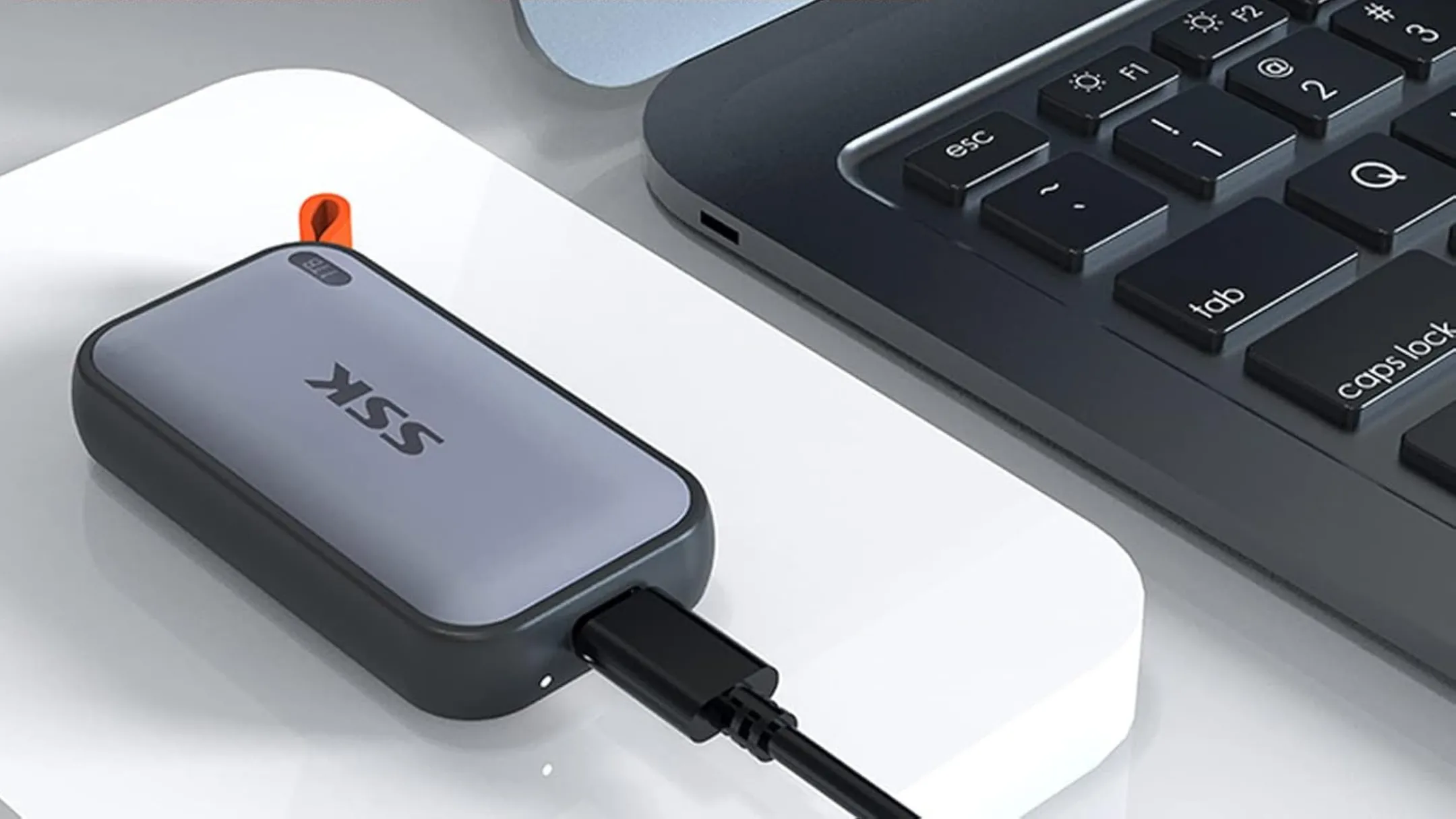 Ổ cứng SSD di động SSK bên cạnh máy tính cá nhân, minh họa khả năng kết nối linh hoạt