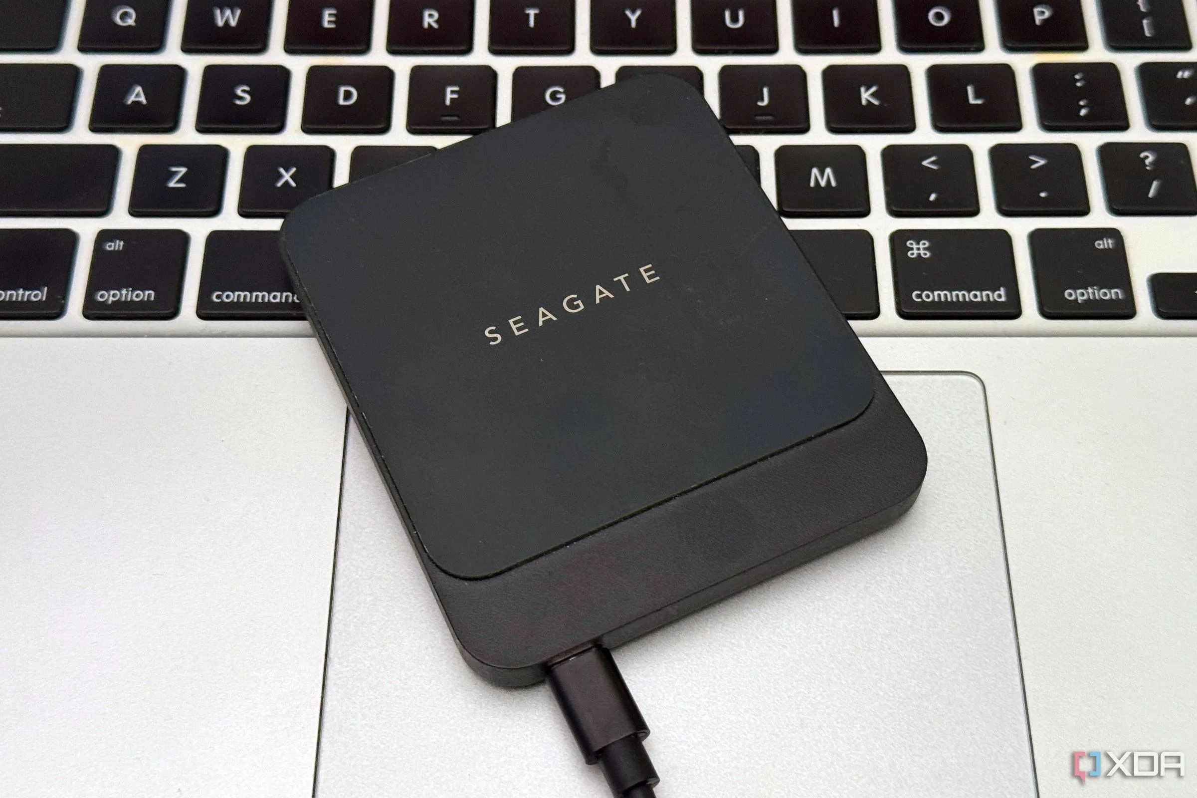 Ổ cứng SSD rời nhỏ gọn màu đen đặt trên touchpad của laptop MacBook