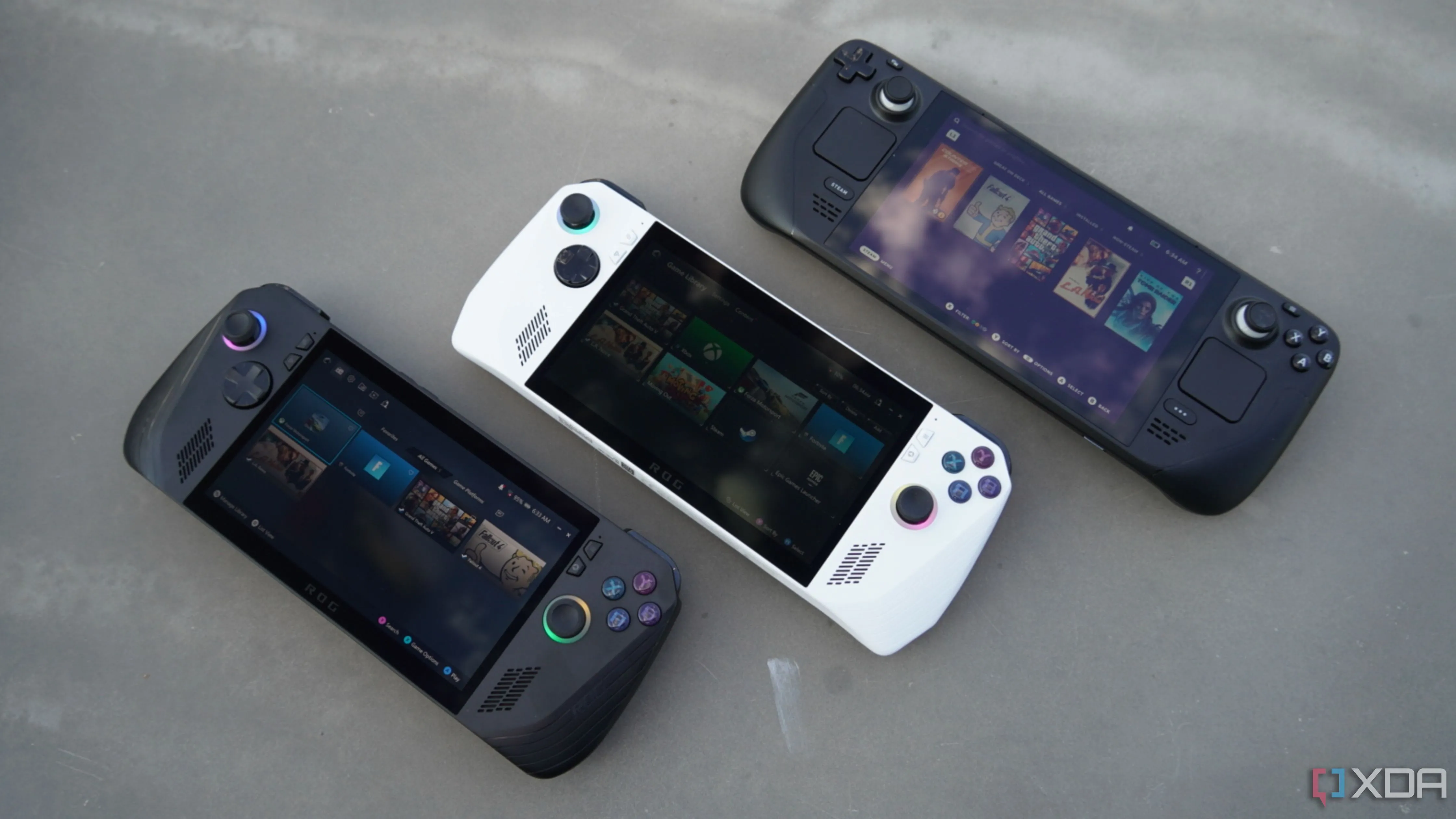 So sánh ba thiết bị chơi game cầm tay: ROG Ally X, ROG Ally và Steam Deck đặt cạnh nhau trên bàn