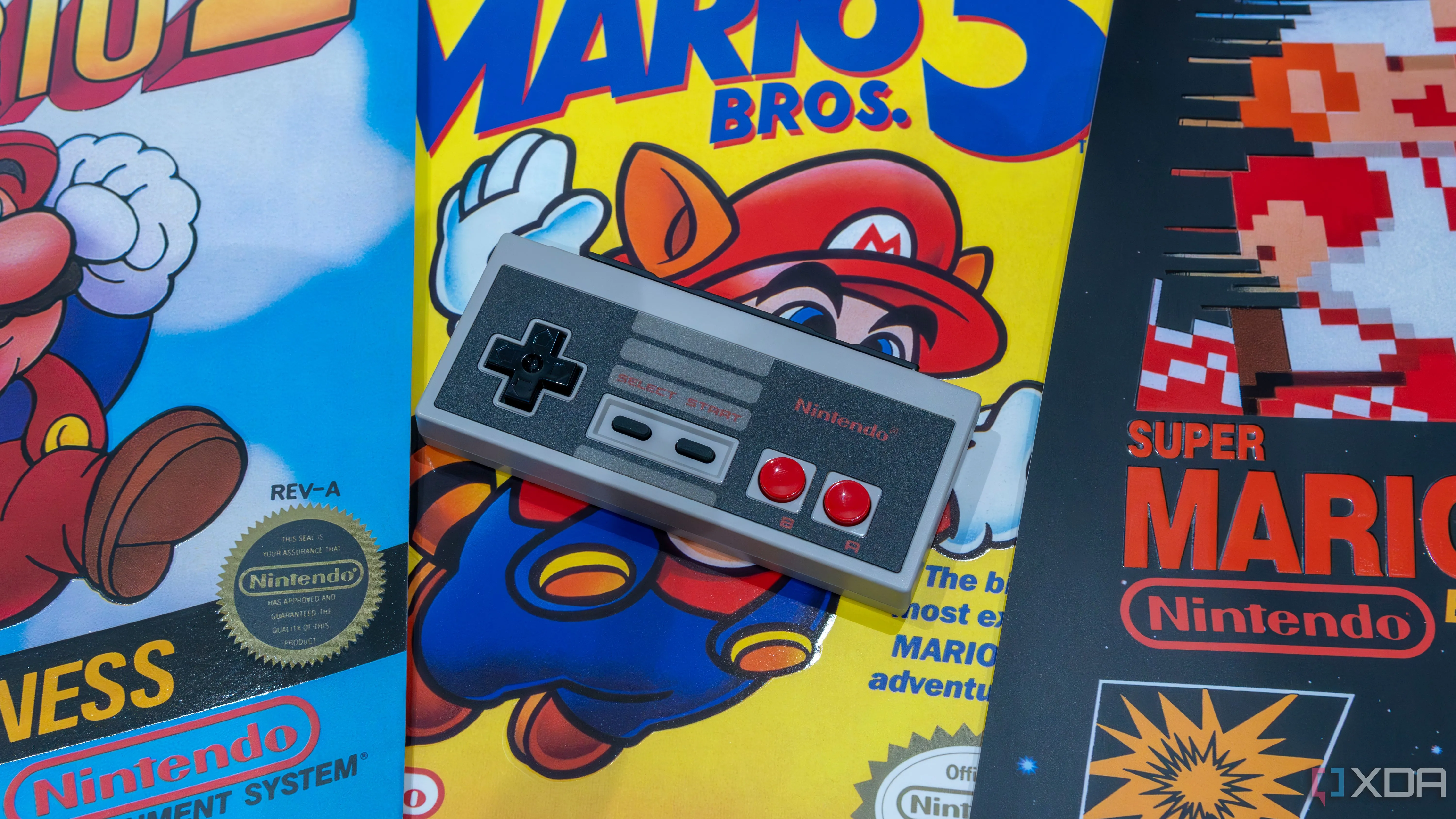 Tay cầm NES phong cách cổ điển cho Nintendo Switch đặt trên hình ảnh các trò chơi Mario, gợi nhớ di sản game Nintendo