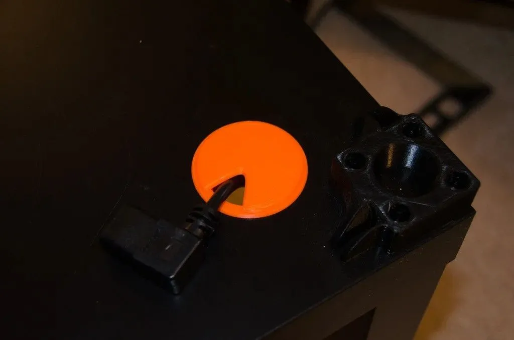 Vòng đệm luồn cáp in 3D màu đen, với một sợi cáp chạy qua, giúp bàn làm việc gọn gàng và bảo vệ dây cáp hiệu quả.